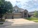 Two-story home featuring a stone entrance, a three-car garage, and a driveway and lawn at 14096 Roaring Fork Cir, Broomfield, CO 80023