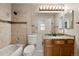 Well-lit bathroom featuring a tub shower with tan tile, a granite vanity, and a large mirror at 11519 Wray Ct, Parker, CO 80134