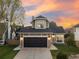 Charming two-story home with a well-maintained lawn and a two-car garage with stone accents, under a vibrant sunset sky at 11519 Wray Ct, Parker, CO 80134