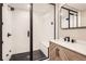 Bathroom with glass-enclosed shower with white subway tile and black hardware and marble countertop at 8768 Foxfire St, Firestone, CO 80504