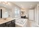 Bright bathroom featuring double vanity, soaking tub under a window, and separate glass enclosed shower at 8768 Foxfire St, Firestone, CO 80504