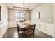 Elegant dining room with wainscoting, hardwood floors, and a large window overlooking the yard at 8768 Foxfire St, Firestone, CO 80504