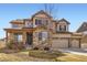 Charming two-story home with a stone facade, three-car garage, well-kept landscaping, and covered front porch at 8768 Foxfire St, Firestone, CO 80504