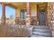 Inviting front porch with stone pillars, seating, and a decorative wreath on the front door at 8768 Foxfire St, Firestone, CO 80504