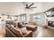 Open-concept living room with a cozy fireplace, leather furniture, and a ceiling fan at 8768 Foxfire St, Firestone, CO 80504