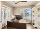 Well-lit office with built-in shelving, hardwood floors, two windows with blinds, and ceiling fan at 8768 Foxfire St, Firestone, CO 80504