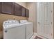 Laundry room with white washer and dryer, dark cabinets, and a tiled floor at 12732 Fisher Dr, Englewood, CO 80112