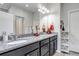 Bathroom featuring double sinks with granite countertops and dark cabinets, and a large mirror at 5519 Genoa St, Denver, CO 80249