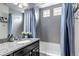 Modern bathroom with granite countertops, gray tiled walls, blue shower curtains, and a white bathtub at 5519 Genoa St, Denver, CO 80249