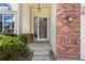 Cozy front porch with brick siding, decorative lighting, and manicured shrubbery at 8985 Edgewood Ln, Highlands Ranch, CO 80130