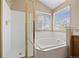 Bathroom featuring glass enclosed shower, soaking tub, and natural light from the window at 8985 Edgewood Ln, Highlands Ranch, CO 80130