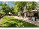 Tree-lined courtyard with grass and walkways plus outdoor seating and red patio umbrellas at 2193 Arapahoe St # 15, Denver, CO 80205