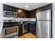 Kitchen with stainless steel appliances, black countertops, and dark cabinets at 2193 Arapahoe St # 15, Denver, CO 80205