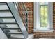 Interior staircase featuring a metal railing and a brick wall with a window at 2193 Arapahoe St # 15, Denver, CO 80205