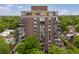 Full exterior view of high-rise apartment building featuring open-air balconies and abundant trees for scenic views at 1150 Vine St # 306, Denver, CO 80206