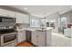 Well-appointed kitchen featuring white cabinets, stainless steel appliances, and breakfast bar opening to the living area at 15921 Bluebonnet Dr, Parker, CO 80134