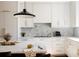 Modern kitchen with white cabinets, marble backsplash, gold hardware and unique pendant lighting at 3130 Wyandot St, Denver, CO 80211