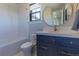 Bright bathroom with a tub, blue vanity with gold handles, and a round mirror at 10704 Flowerburst Ct, Highlands Ranch, CO 80126