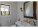 Chic powder room featuring a marble countertop, decorative fixtures, and a stylish mirror with a dark frame at 10704 Flowerburst Ct, Highlands Ranch, CO 80126
