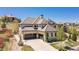 View of stone home with a three car garage and landscaped front yard at 10704 Flowerburst Ct, Highlands Ranch, CO 80126