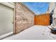 The backyard featuring a brick wall, door, wooden fence, and snow-covered ground at 7729 S Cove Cir, Centennial, CO 80122