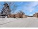 Exterior view featuring brick construction, snow-covered ground, and attached garages at 7729 S Cove Cir, Centennial, CO 80122