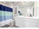 Well-lit bathroom features a large white vanity, commode and a blue and green shower curtain at 9334 Sedalia St, Commerce City, CO 80022