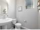 Cozy bathroom with pedestal sink, toilet, natural light from a window, and neutral color palette at 9334 Sedalia St, Commerce City, CO 80022