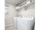 Bright laundry room with a side by side white washer and dryer and upper shelving at 9334 Sedalia St, Commerce City, CO 80022