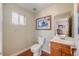 Bathroom with a single vanity, toilet, window, and framed print, showing entry to a room with a crib at 2047 S Franklin St, Denver, CO 80210