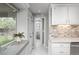Bright kitchen featuring white cabinetry, mosaic backsplash, and views into the hallway and bedroom at 8151 S Marshall Ct, Littleton, CO 80128