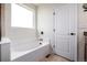 Bright bathroom featuring a white tile-surround tub with sleek fixtures near a window and door at 42425 Forest Oaks Dr, Elizabeth, CO 80107