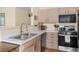 Well-lit kitchen with stainless steel sink, modern appliances, light wood cabinets, and a functional design for easy cooking at 8405 Pebble Creek Way # 202, Highlands Ranch, CO 80126