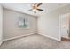 Bedroom features neutral carpet, a ceiling fan, and natural light from a large window at 3573 S Lisbon Ct, Aurora, CO 80013