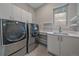 Contemporary laundry room features modern washer/dryer, sleek countertops, shelving, and a bright window with natural light at 726 Dreamcatcher Ln, Evergreen, CO 80439