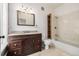Bathroom with a dark wood vanity, tile floors, a large mirror, and a tiled shower-tub combo at 1210 E Colfax Ave # 301, Denver, CO 80218