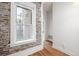 Bedroom featuring exposed brick, a window with natural light, and hardwood floors, creating a cozy and inviting space at 1210 E Colfax Ave # 301, Denver, CO 80218