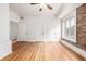 Bedroom featuring hardwood floors, an exposed brick wall, a ceiling fan, and multiple doors at 1210 E Colfax Ave # 301, Denver, CO 80218