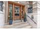 Close-up of the building's elegant wooden front door with stylish potted plants and secure entry system at 1210 E Colfax Ave # 301, Denver, CO 80218