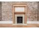 A charming fireplace with wooden mantel set against an exposed brick wall and hardwood floors at 1210 E Colfax Ave # 301, Denver, CO 80218