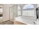 Bathroom featuring a glass enclosed shower, tub with tile surround, and unique glass block window detail at 21093 E 53Rd Ave, Denver, CO 80249