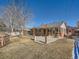 Brick home's backyard features a patio, lawn, and mature trees at 2525 Nelson St, Lakewood, CO 80215