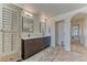 This bathroom features double sinks, dark wood cabinets, and neutral tile flooring at 9274 Viaggio Way, Highlands Ranch, CO 80126