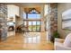 Elegant living room with hardwood floors, a stone fireplace, a grand piano and large windows overlooking outdoors at 19155 Lochmere Ct, Monument, CO 80132