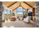 Bright living room with vaulted wood ceilings, a stone fireplace, and large windows that offer a scenic view at 19155 Lochmere Ct, Monument, CO 80132