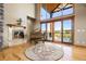 Elegant living room with hardwood floors, a stone fireplace, a grand piano and large windows overlooking outdoors at 19155 Lochmere Ct, Monument, CO 80132