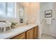 Bright bathroom with white countertops, wood cabinets, large mirror, and a decorative plant at 13093 W Cedar Dr # 121, Lakewood, CO 80228