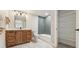 Bright bathroom with a wood vanity, large mirror, tiled shower, and open storage at 1361 Art Dr, Berthoud, CO 80513