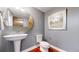 Stylish half bathroom with a pedestal sink, modern toilet, and decorative mirror at 8041 E 29Th Ave, Denver, CO 80238