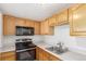 Kitchen featuring wood cabinets, black appliances, and neutral countertops at 9725 E Harvard Ave # 317, Denver, CO 80231